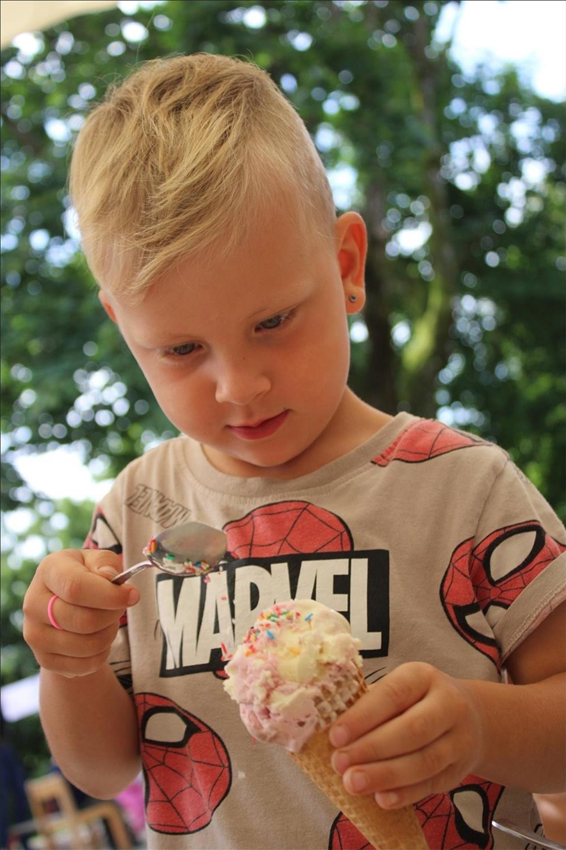 Kind hält eine Eiswaffel mit bunten Streuseln im Garten des Kindergartens.