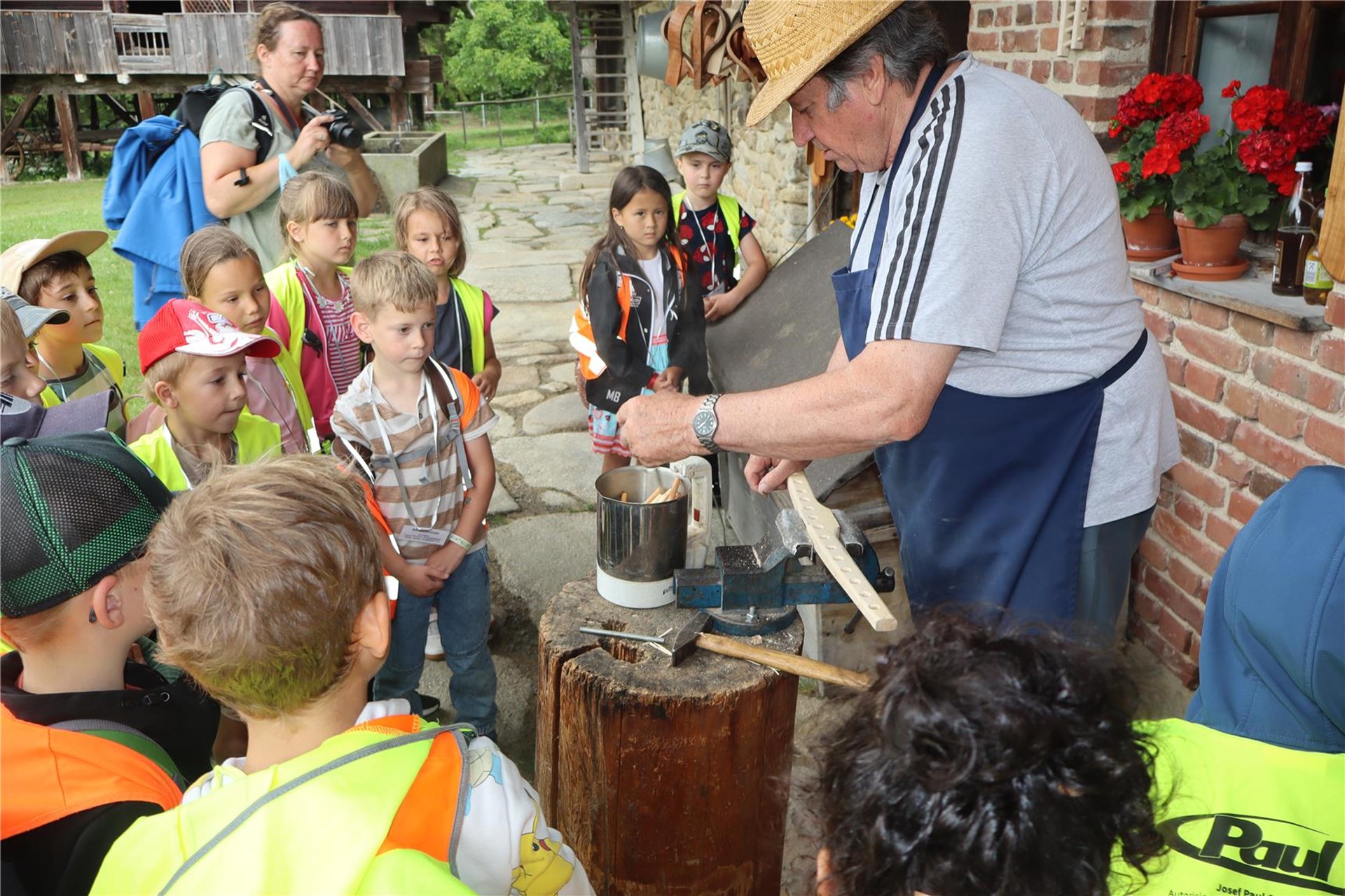 Kinder mit Warnwesten beobachten einen Handwerker im Freilichtmuseum Finsterau.