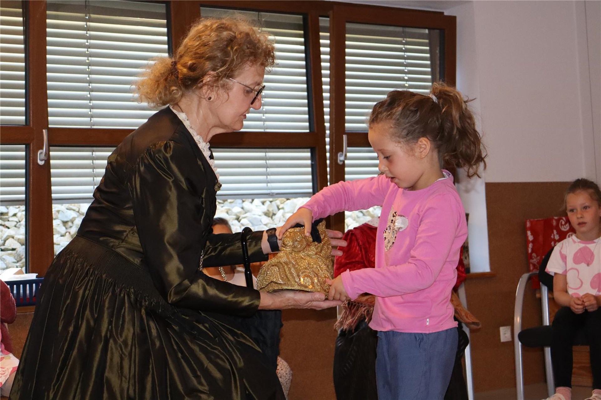 Goldhaubenfrau zeigt Mädchen ihre Goldhaube.