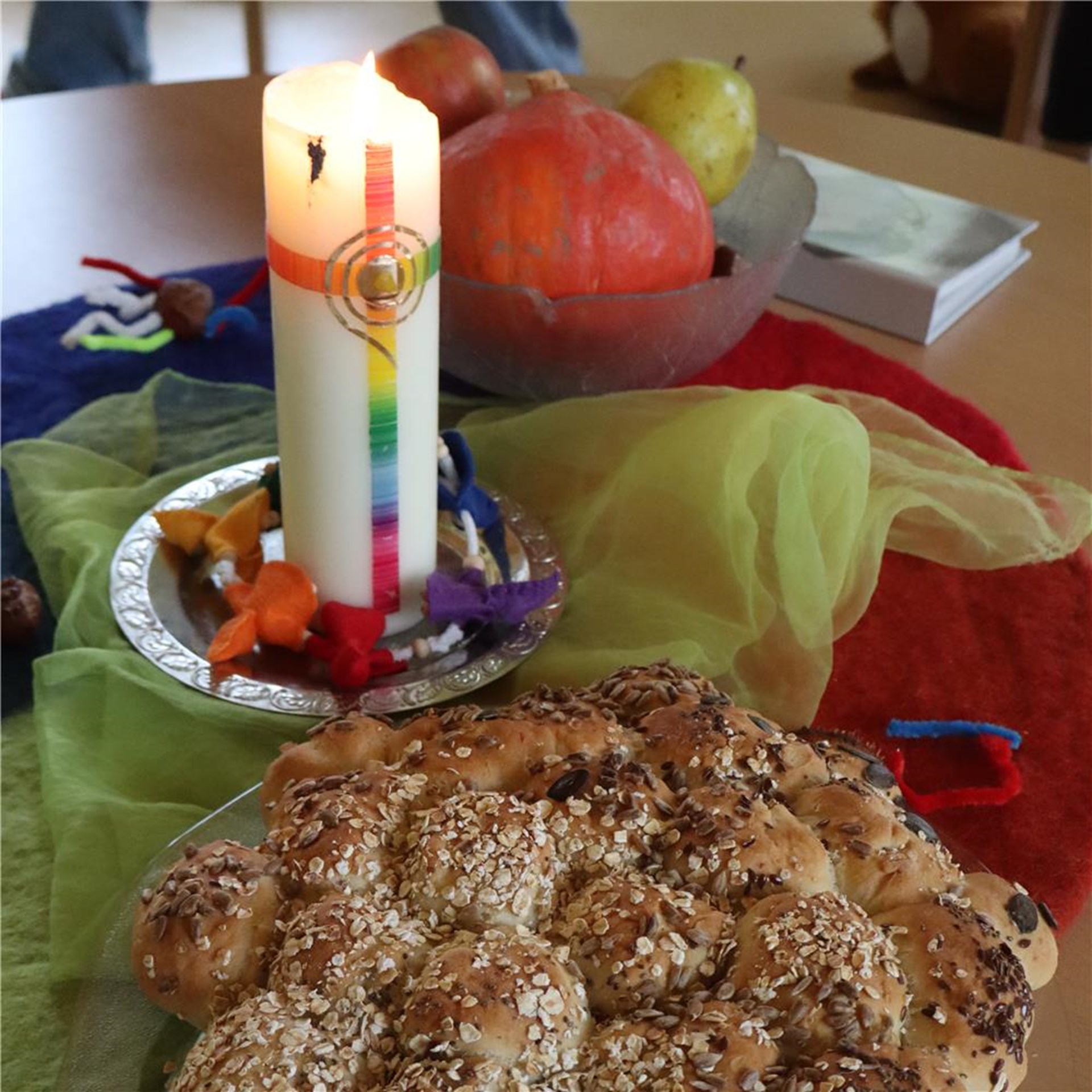 Ein gedeckter Tisch mit einer brennenden Kerze und einem Teller mit Speisen.