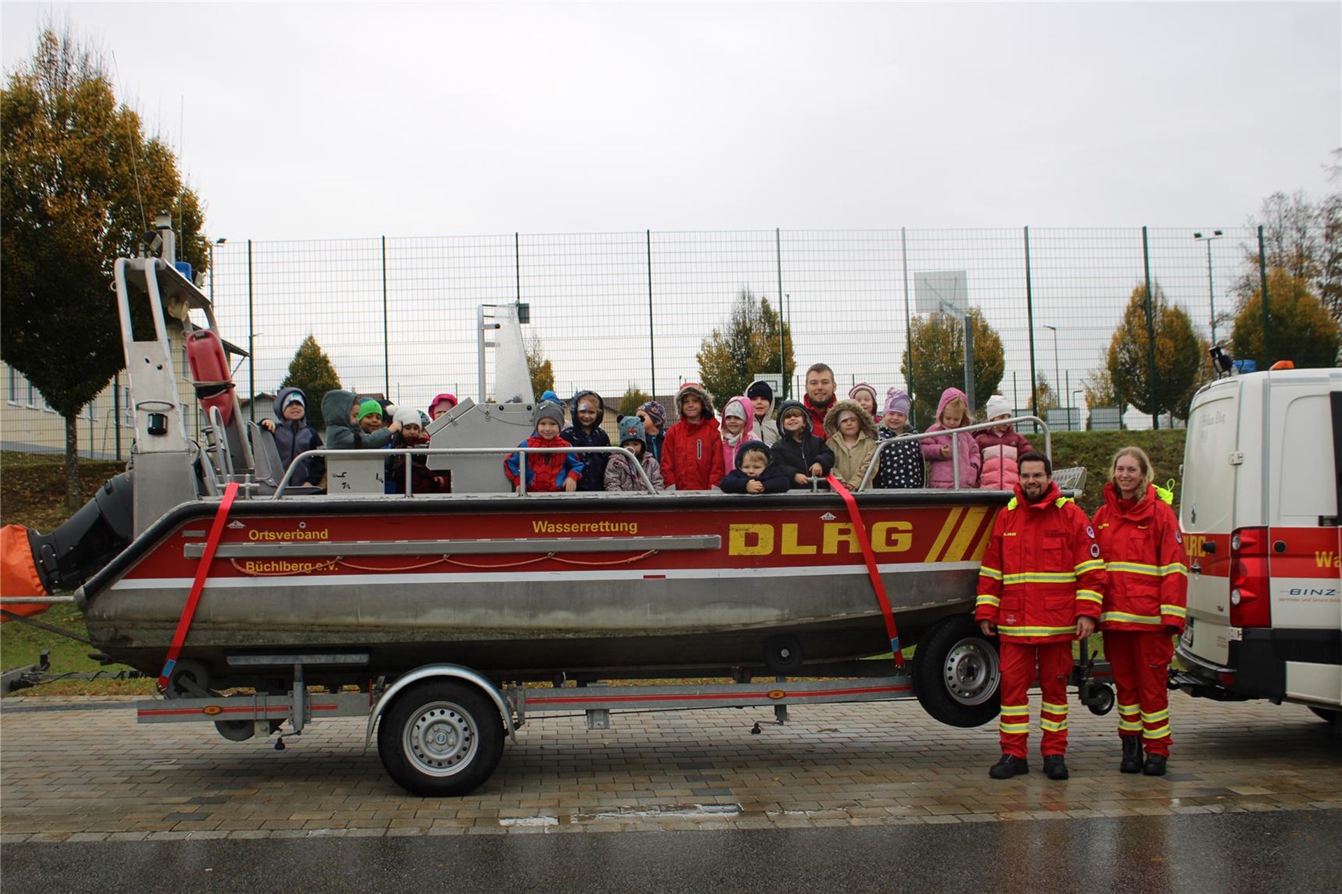 Eine Gruppe von Menschen steht neben einem Boot am Wasser.